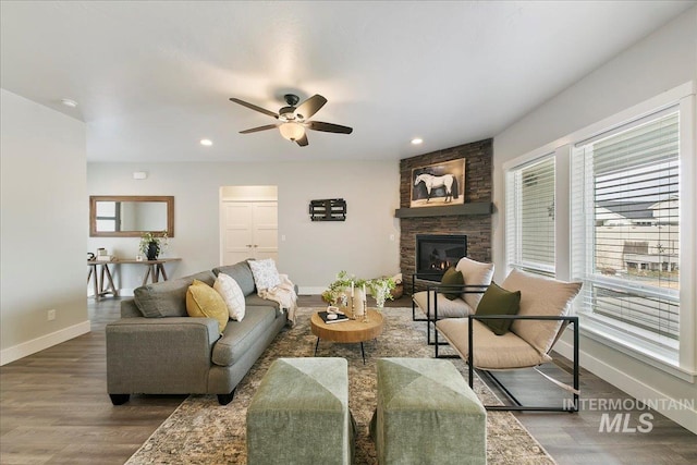 living room featuring a ceiling fan, wood finished floors, recessed lighting, a stone fireplace, and baseboards