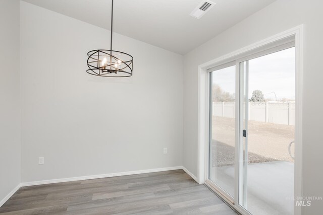 11069 Canvas St, Caldwell, ID 83605 - unfurnished dining area with baseboards, visible vents, wood finished floors, and an inviting chandelier