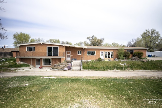 view of front of house featuring stairs, brick siding, and a front lawn