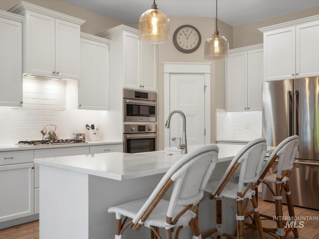 kitchen with white cabinets, tasteful backsplash, a breakfast bar, and stainless steel appliances