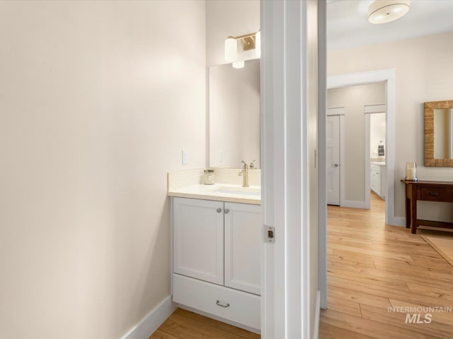 bathroom featuring baseboards, decorative backsplash, wood finished floors, and vanity