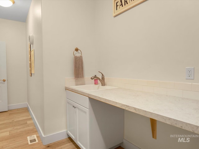 bathroom featuring visible vents, baseboards, wood finished floors, and vanity