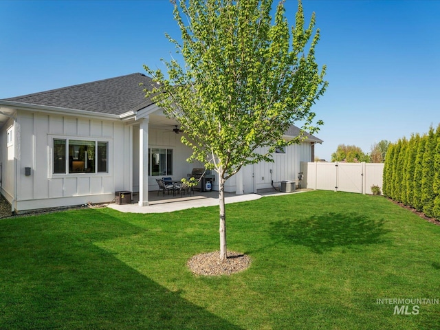 back of house with a shingled roof, board and batten siding, ceiling fan, a gate, and a patio area