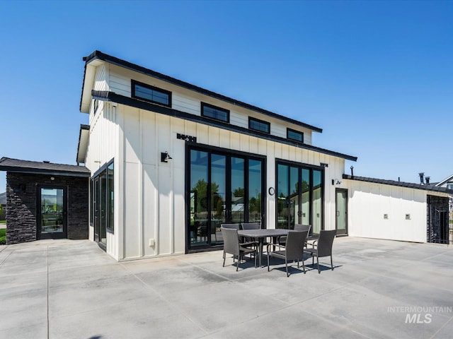 rear view of house featuring a patio, outdoor dining area, and board and batten siding