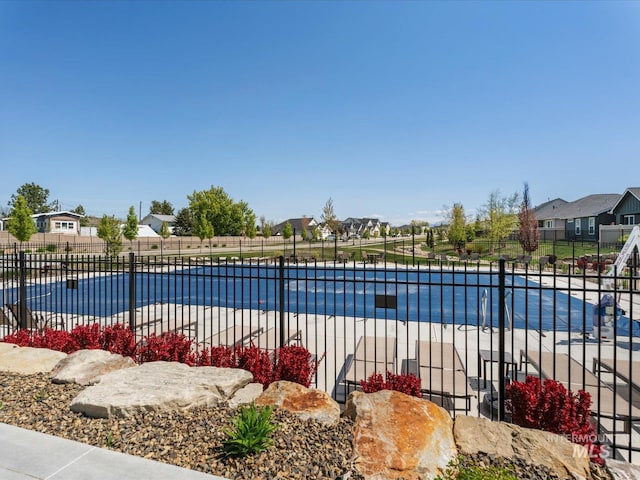 pool featuring fence, a patio, and a residential view