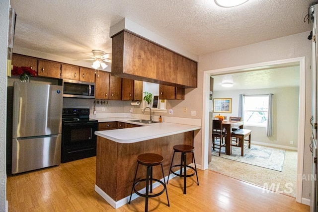 1627 Verdant Ct, Emmett, ID 83617 - kitchen with stainless steel appliances, a sink, brown cabinets, light wood finished floors, and a peninsula
