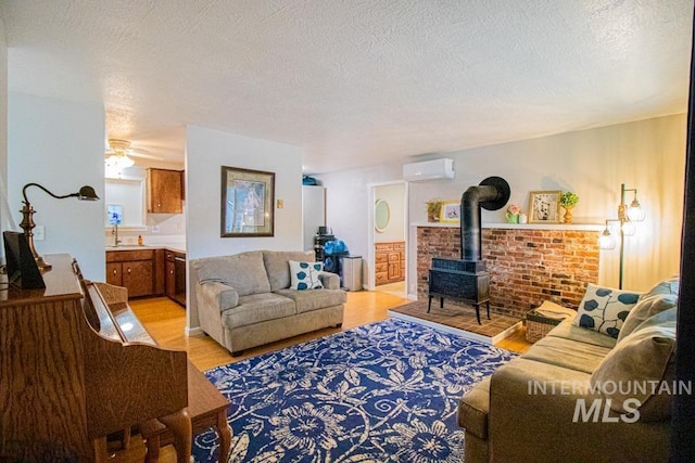 1627 Verdant Ct, Emmett, ID 83617 - living area with a wall mounted AC, light wood finished floors, a wood stove, a textured ceiling, and ceiling fan