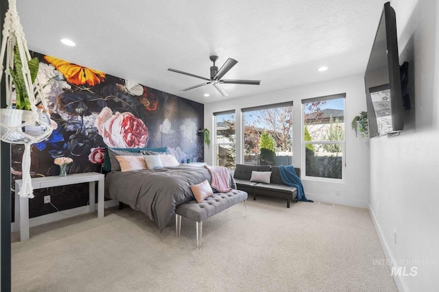 carpeted bedroom featuring ceiling fan and a textured ceiling