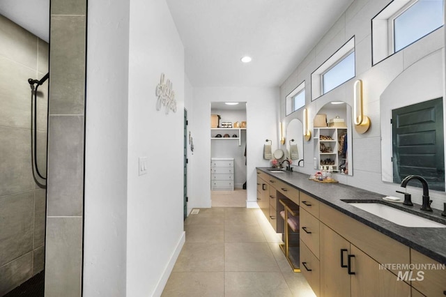 bathroom featuring a tile shower, vanity, and tile patterned floors