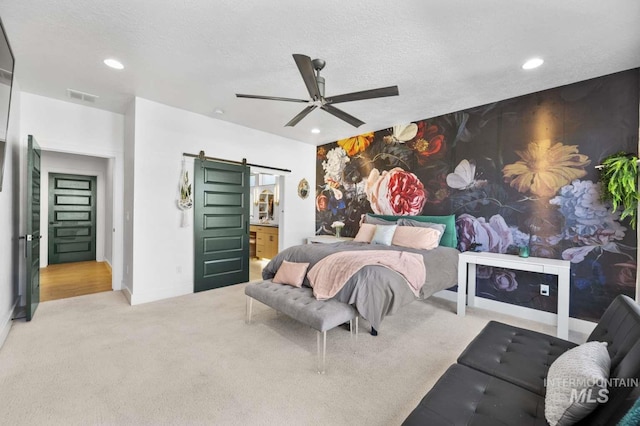 carpeted bedroom featuring a barn door, ceiling fan, and a textured ceiling