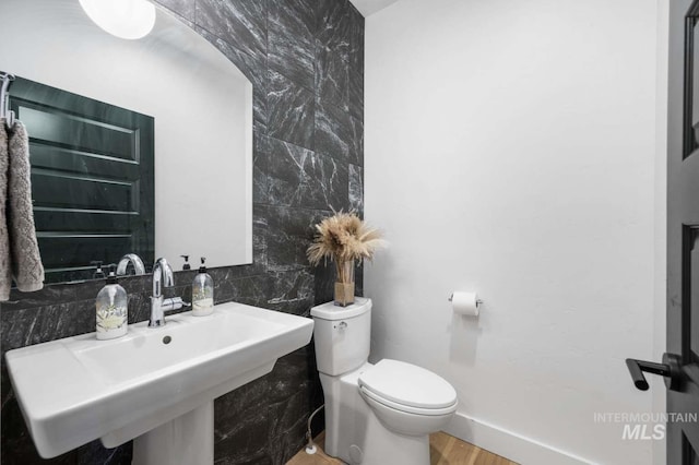 bathroom with hardwood / wood-style flooring, sink, toilet, and tile walls