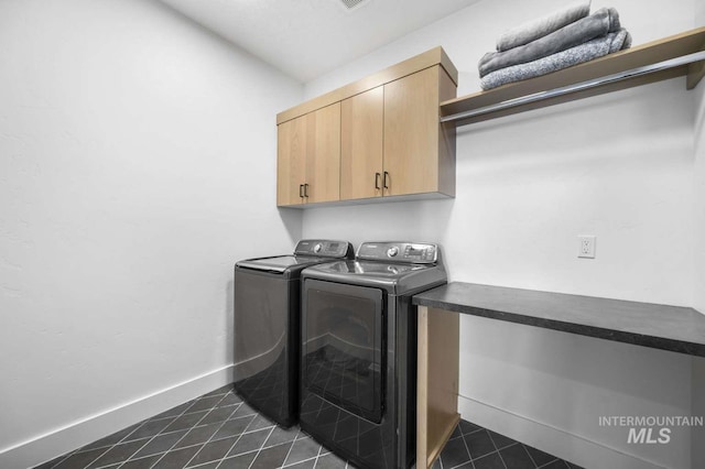 washroom featuring separate washer and dryer, cabinets, and dark tile patterned flooring