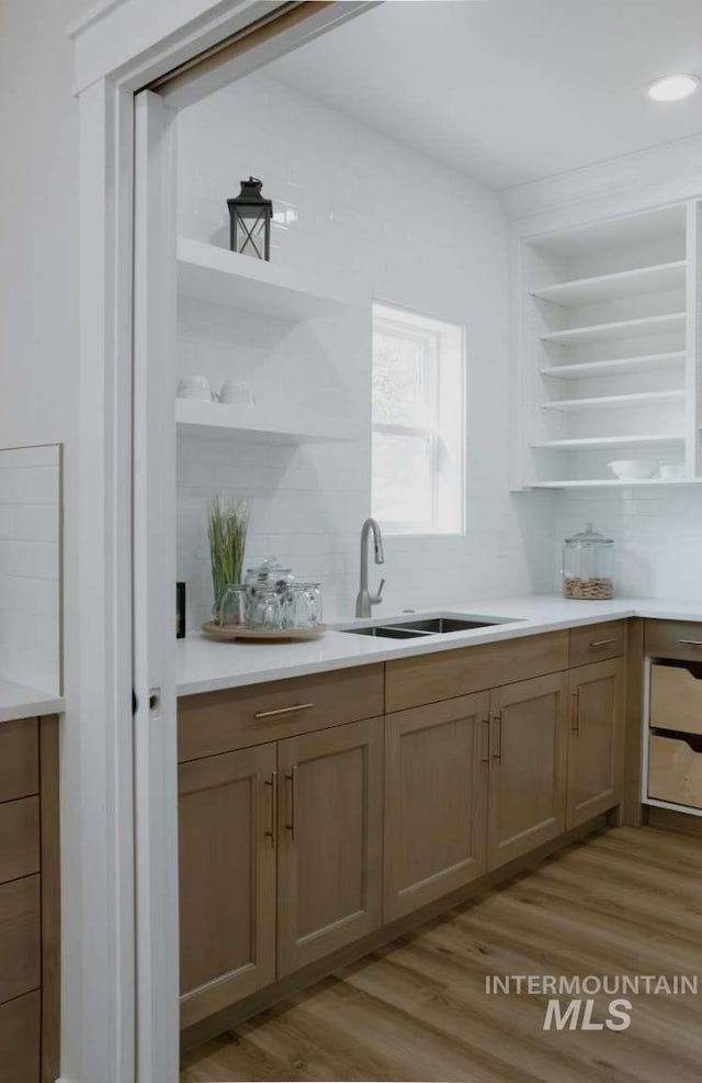 kitchen with backsplash, sink, and light wood-type flooring