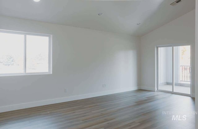 spare room featuring hardwood / wood-style floors and vaulted ceiling