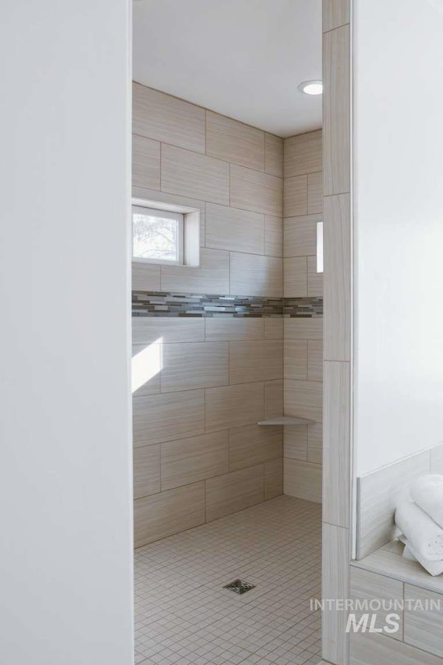 bathroom with tiled shower and tile patterned floors