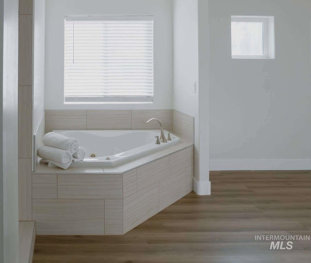 bathroom featuring tiled bath and hardwood / wood-style flooring