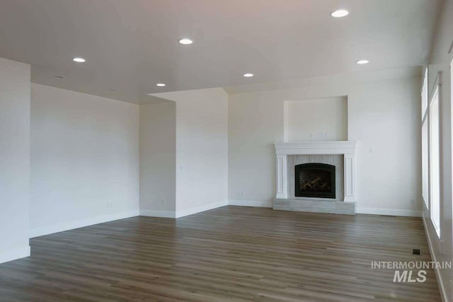 unfurnished living room with dark hardwood / wood-style flooring and a brick fireplace