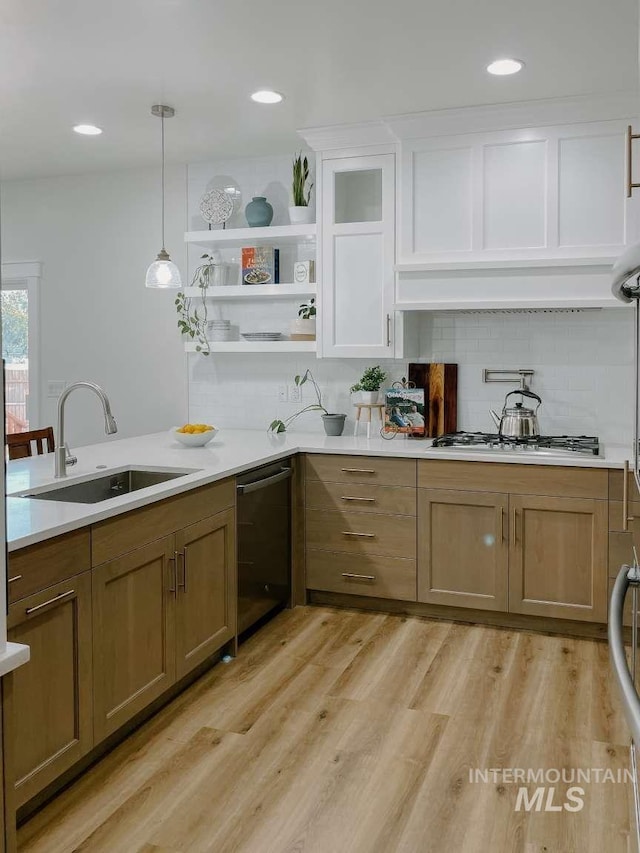 kitchen featuring white cabinetry, sink, stainless steel appliances, hanging light fixtures, and light hardwood / wood-style floors