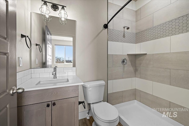 full bath featuring tiled shower, vanity, and toilet