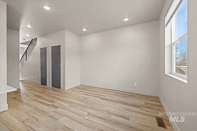 empty room featuring light wood-style floors, baseboards, visible vents, and recessed lighting