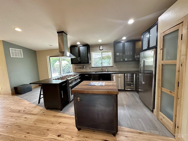 kitchen with island exhaust hood, visible vents, a center island, a sink, and stainless steel appliances
