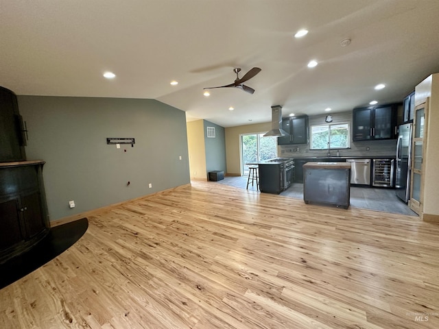 kitchen with a sink, light wood-style floors, a center island, stainless steel appliances, and island range hood
