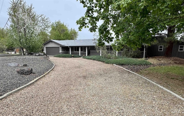 ranch-style house featuring a garage and gravel driveway