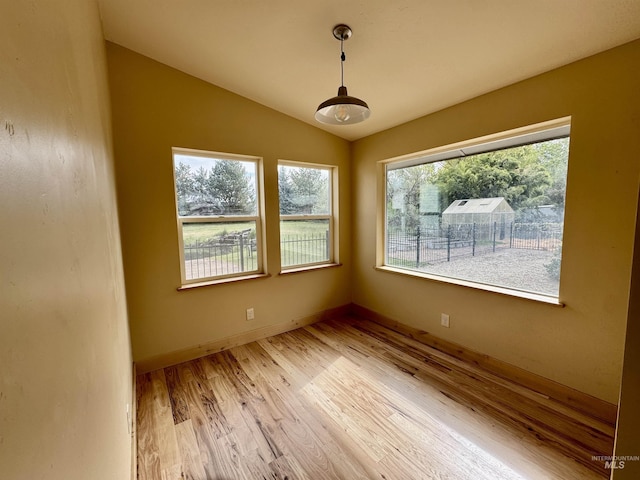 unfurnished room with baseboards, light wood-type flooring, and lofted ceiling