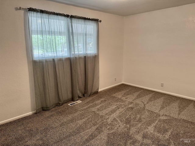 empty room with visible vents, baseboards, and dark carpet