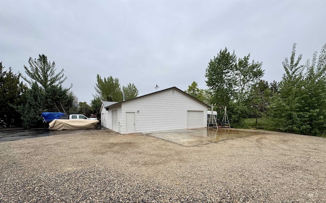 view of home's exterior featuring a detached garage, an outdoor structure, and gravel driveway