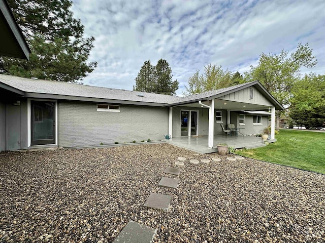 back of house featuring brick siding and a yard