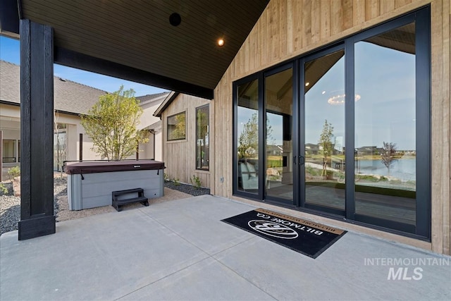 view of patio / terrace featuring a water view and a hot tub