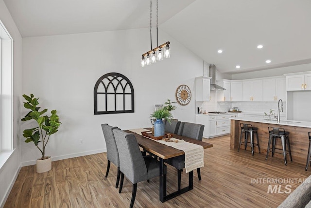 dining area with high vaulted ceiling, light hardwood / wood-style flooring, and sink