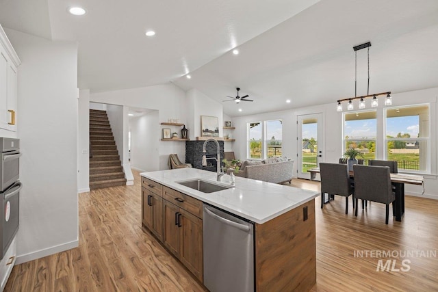 kitchen featuring dishwasher, a center island with sink, sink, ceiling fan, and light hardwood / wood-style floors