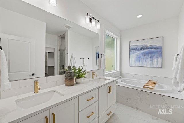 bathroom with vanity and a relaxing tiled tub