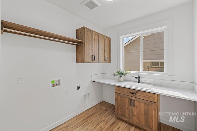 clothes washing area with sink, cabinets, electric dryer hookup, light hardwood / wood-style flooring, and hookup for a washing machine