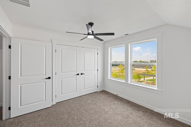 unfurnished bedroom featuring carpet flooring, ceiling fan, a closet, and lofted ceiling