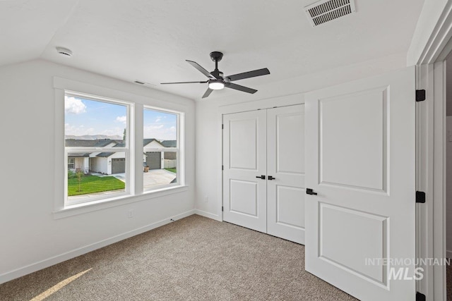 unfurnished bedroom with ceiling fan, light colored carpet, lofted ceiling, and a closet