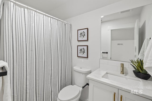 bathroom featuring decorative backsplash, vanity, toilet, and walk in shower