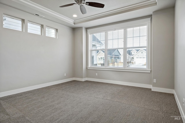 carpeted spare room with a raised ceiling, ceiling fan, and ornamental molding