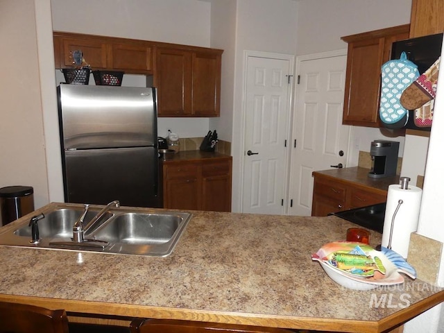 24 Mangum Dr Unit 1, Donnelly, ID 83615 - kitchen with freestanding refrigerator, a sink, brown cabinets, and light countertops
