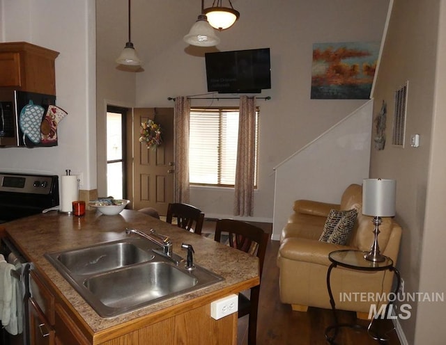 24 Mangum Dr Unit 1, Donnelly, ID 83615 - kitchen with range with electric cooktop, stainless steel microwave, a sink, brown cabinetry, and decorative light fixtures