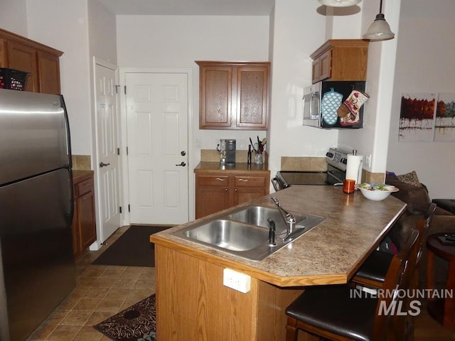 24 Mangum Dr Unit 1, Donnelly, ID 83615 - kitchen featuring appliances with stainless steel finishes, a sink, a peninsula, brown cabinets, and a breakfast bar