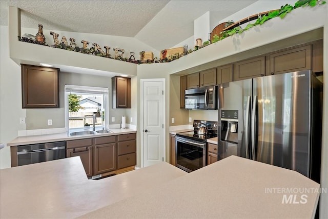 3804 Stonehedge Way, Caldwell, ID 83605 - kitchen featuring appliances with stainless steel finishes, light countertops, vaulted ceiling, and a textured ceiling