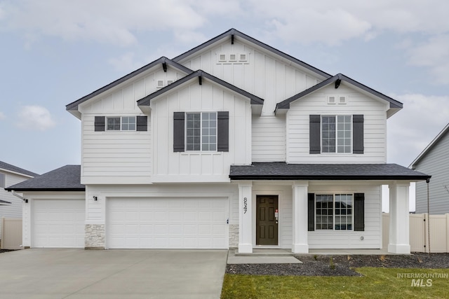 view of front facade with fence, driveway, an attached garage, a shingled roof, and board and batten siding