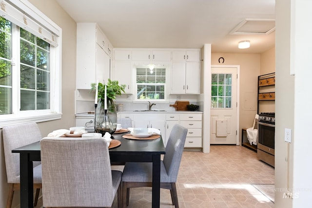 kitchen featuring stainless steel range oven, white cabinetry, sink, and a wealth of natural light