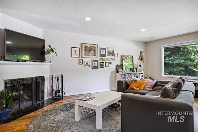 1207 N 19th St, Boise, ID 83702 - living room with wood finished floors, a tiled fireplace, recessed lighting, and baseboards