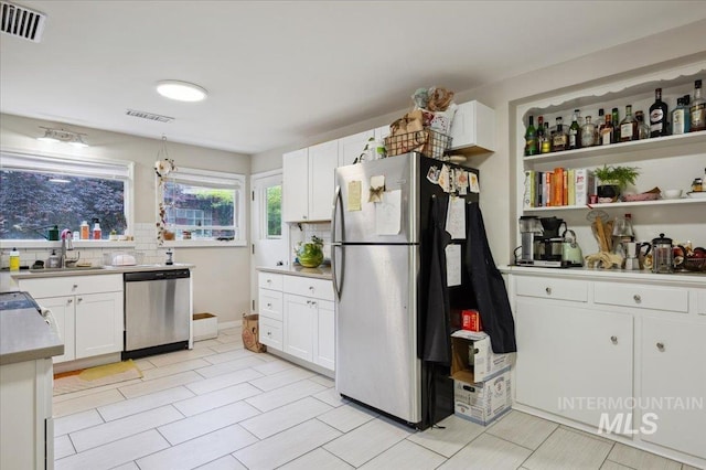 1207 N 19th St, Boise, ID 83702 - kitchen with appliances with stainless steel finishes, a sink, white cabinetry, light countertops, and backsplash