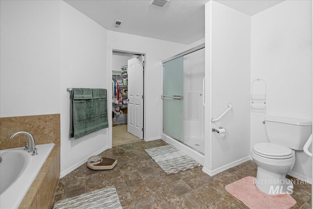 bathroom featuring plus walk in shower, a textured ceiling, and toilet