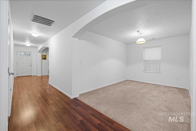 unfurnished room with dark hardwood / wood-style flooring and a textured ceiling